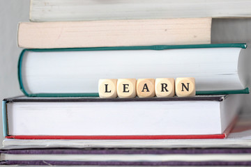 Books on desk with dice word learn as motivation