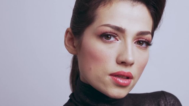Beautiful woman with bright vivid makeup. Sexy adult girl with colorful eye makeup.  Pink make-up of eyes. Closeup caucasian face of a  fashion model. Slow motion footage. 