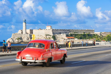 Amerikanischer roter Cabriolet Oldtimer fährt auf dem berühmten Malecon der Festung Castillo de...