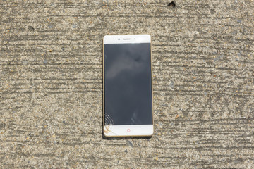 Broken screen smartphone falls down on the concrete floor