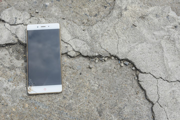 Broken screen smartphone falls down on the concrete floor