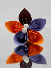 An orange and violet origami flower on white background