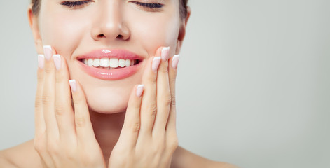 Perfect woman smile and manicured hand. French manicure and pink lipgloss makeup
