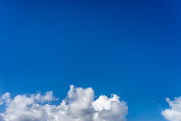 Fluffy white clouds against a bright, colorful blue sky