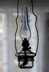 An old and rustic oil lamp hanging in dusky room