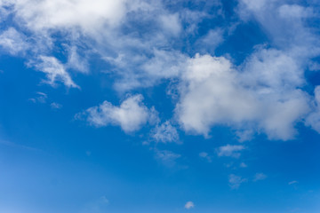 Naklejka na ściany i meble Fluffy white clouds against a bright, colorful blue sky
