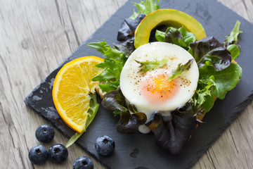 Fried eggs with bread toast on lettuce in a black plate.