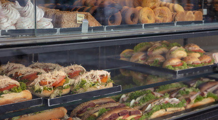 Sandwiches variety and sweets on a store glass display, closeup view