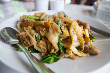 Stir fry noodles  in white bowl.