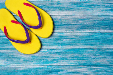 Bright yellow flip flops as concept of vacation time on blue background