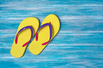 Bright yellow flip flops as concept of vacation time on blue background