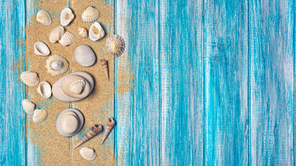 Obraz na płótnie Canvas Sand with seashells on blue background as concept of vacation time