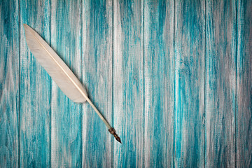 Vintage quill pen on blue wooden background