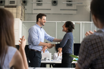 Happy young business people handshaking in office 
