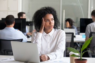 Black female sitting at work suffering from headache