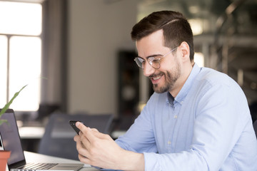 Fototapeta premium Happy businessman reading message looking at phone screen