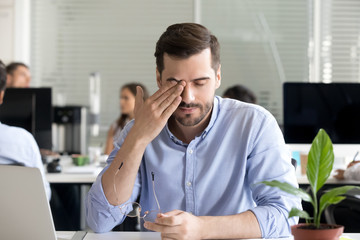 Office worker taking off glasses rubbing tired eyes 