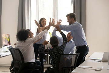 Diverse group of people giving high five in office