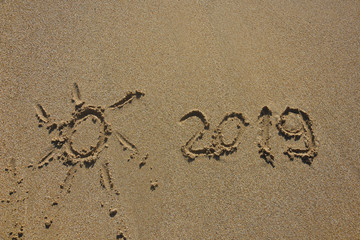 Summer vacation concept. Summer 2019 written on wet sand at the beach