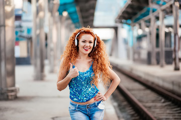 Red-haired little girl listening to music on headphones.