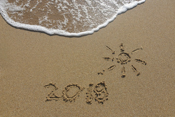 Summer vacation concept. Summer 2019 written on wet sand at the beach
