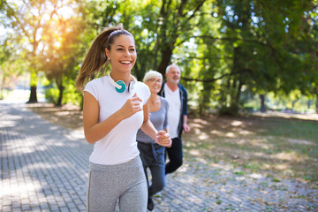 Senior man and woman and young female instructor  workout on fresh air. Outdoor activities, healthy...