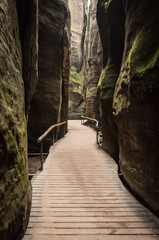 A wooden path leads through high mossy rock walls.