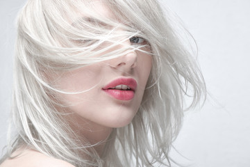 Portrait of a young beautiful blonde woman with plump red lips on a white background close up....