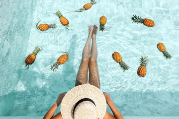 Girl relaxing in pool with pineapples