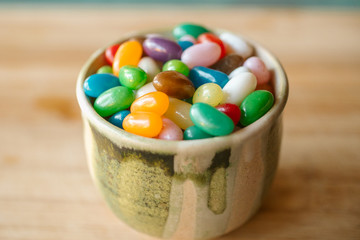 Jelly candy beans on a bowl. Close up view of candy beans with selective focus on wooden background.  