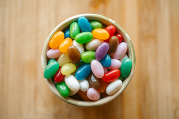 Jelly candy beans on a bowl. Close up view of candy beans with selective focus on wooden background.  