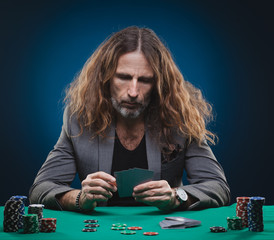 Long-haired handsome man playing poker in a casino.