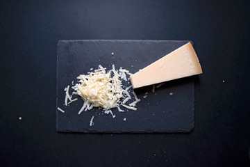 Grana padano grated, italian cheese on black backgound