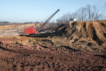Excavator in the red clay quarry. Industrial background