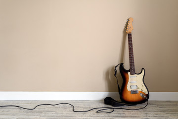 Electro guitar with cable on wall background. Music instrument concept