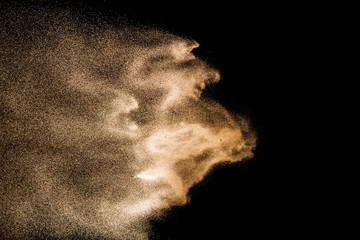 Golden sand explosion isolated on black background. Abstract sand cloud. Golden colored sand splash...