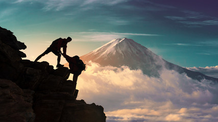 Young asian couple hikers climbing up on the peak of mountain near mountain fuji .Climbing ,Helps and Team work concept 