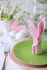 Happy easter. Decor and table setting of the Easter table is a vase with pink tulips and dishes of pink and green color.
