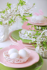 Obraz na płótnie Canvas Happy easter. Decor and table setting of the Easter table is a vase with pink tulips and dishes of pink and green color.