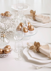 Fototapeta na wymiar Happy Easter! Golden decor and table setting of the Easter table with white dishes of white color.