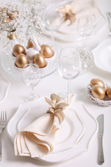 Fototapeta na wymiar Happy Easter! Golden decor and table setting of the Easter table with white dishes of white color.