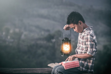 christian Boy holding oil lamp and reading bible, christian concept