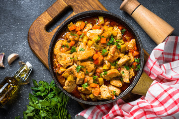 Chicken stew with vegetables black stone table, top view.