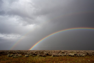 double rainbow and storm clouds over sagebrush in American western state