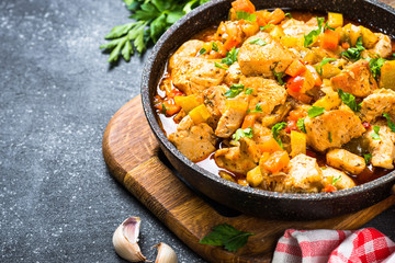 Chicken stew with vegetables black stone table, top view.