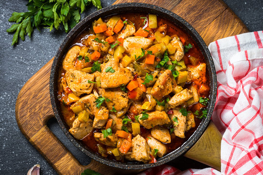 Chicken stew with vegetables black stone table, top view.