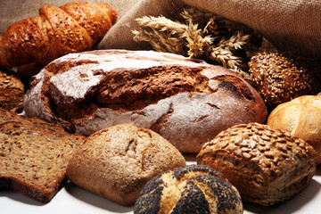 Different kinds of bread and bread rolls on board from above.