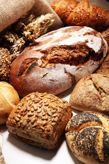 Different kinds of bread and bread rolls on board from above.