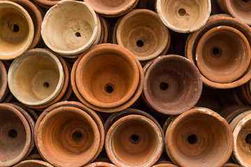 Stacks of terracotta flowerpots in a gardeners potting shed at botanical garden. Many stacked ceramic pots for plants. Old ceramic pots.