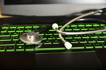 Stethoscope is lying on a green keyboard on a laptop, office equipment repair concept